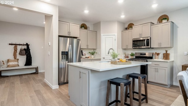 kitchen with light hardwood / wood-style floors, a kitchen island, appliances with stainless steel finishes, and gray cabinets