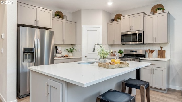 kitchen with sink, a center island with sink, decorative backsplash, and appliances with stainless steel finishes