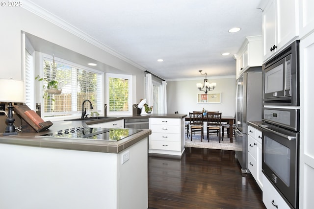 kitchen with ornamental molding, stainless steel appliances, white cabinetry, a peninsula, and a notable chandelier