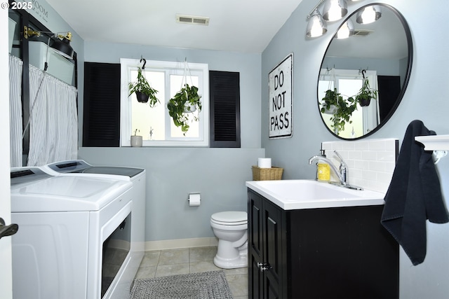 bathroom featuring washing machine and clothes dryer, toilet, vanity, and visible vents