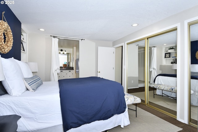 carpeted bedroom with ensuite bathroom and recessed lighting