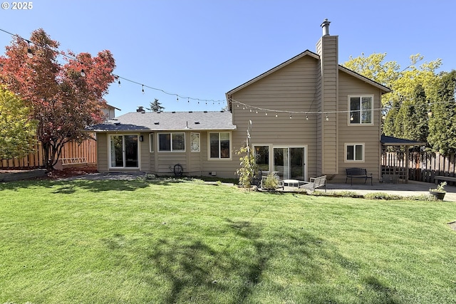 rear view of house featuring a lawn, a chimney, fence, and a patio area
