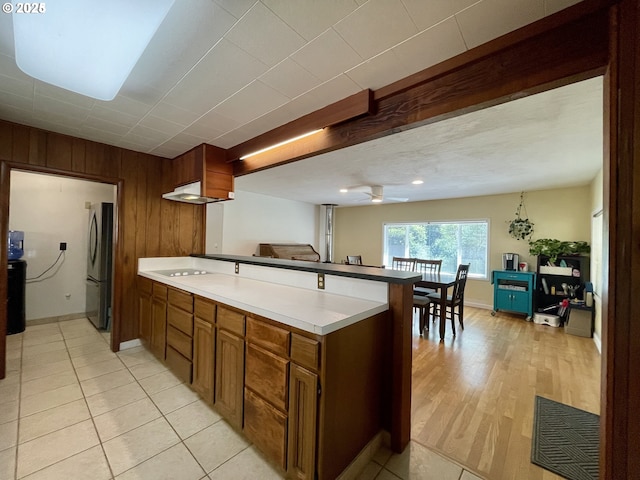 96343 Coos-Sumner Ln, Coos Bay, OR 97420 - kitchen featuring freestanding refrigerator, a peninsula, wood walls, ceiling fan, and light tile patterned flooring