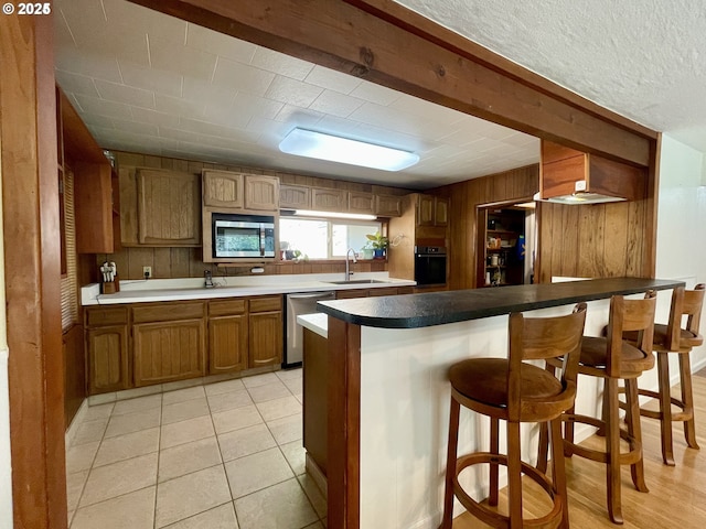 96343 Coos-Sumner Ln, Coos Bay, OR 97420 - kitchen featuring stainless steel appliances, wooden walls, brown cabinetry, a sink, and a breakfast bar area