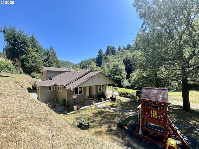 96343 Coos-Sumner Ln, Coos Bay, OR 97420 - view of side of property featuring a playground, a shingled roof, and a yard