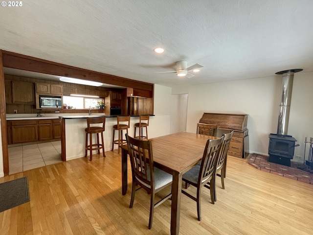 96343 Coos-Sumner Ln, Coos Bay, OR 97420 - dining room featuring light wood-style floors, a wood stove, ceiling fan, recessed lighting, and a textured ceiling