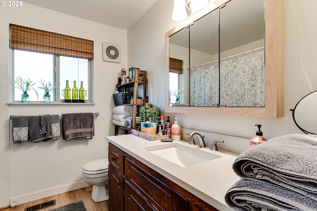 full bath featuring visible vents, vanity, toilet, and wood finished floors