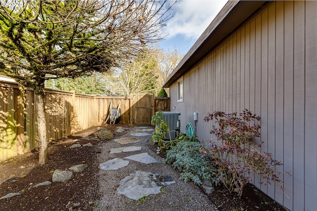 view of property exterior featuring a gate, fence, and cooling unit