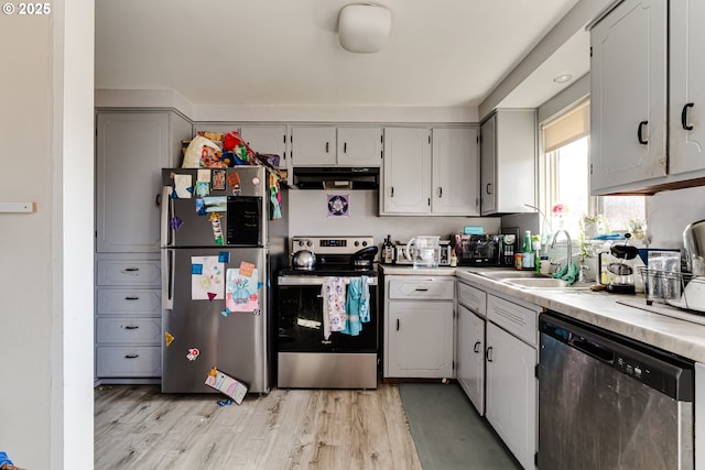 kitchen featuring light wood finished floors, light countertops, stainless steel appliances, a sink, and exhaust hood