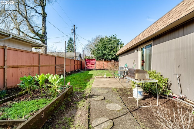 view of yard with a fenced backyard, a vegetable garden, and a patio