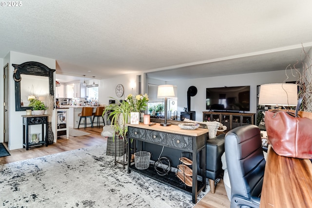 living area featuring a wood stove, a textured ceiling, and wood finished floors