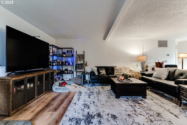 living area with visible vents, a textured ceiling, and wood finished floors