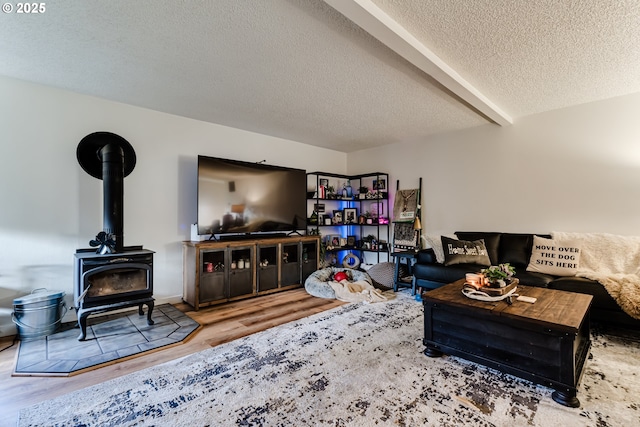 living room with a textured ceiling, wood finished floors, and a wood stove