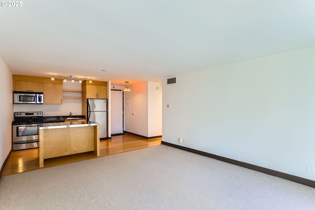 kitchen featuring light brown cabinets, stainless steel appliances, a sink, visible vents, and baseboards