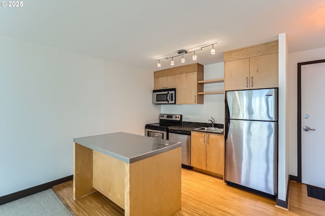 kitchen featuring a sink, appliances with stainless steel finishes, light wood-type flooring, open shelves, and dark countertops