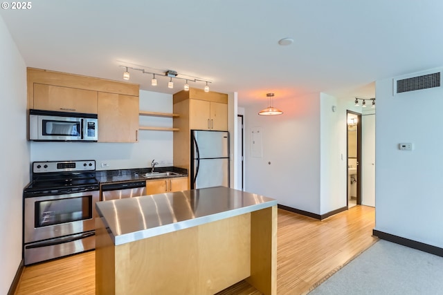 kitchen with light brown cabinets, stainless steel appliances, a sink, visible vents, and light wood-style floors