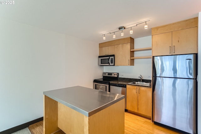 kitchen featuring stainless steel appliances, a sink, open shelves, light wood finished floors, and dark countertops