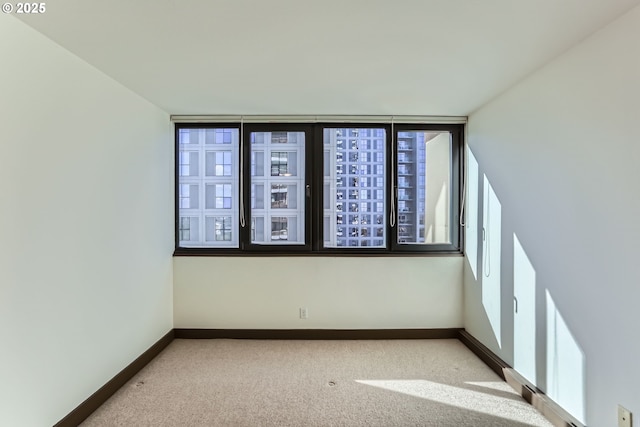 unfurnished room featuring carpet and baseboards