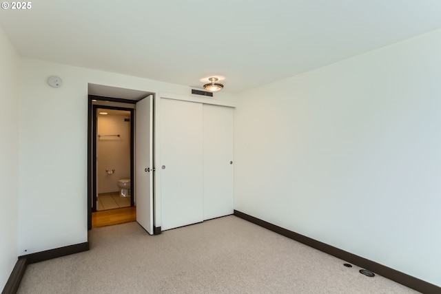 unfurnished bedroom with a closet, light carpet, visible vents, and baseboards