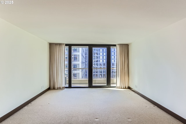 carpeted empty room with floor to ceiling windows and baseboards