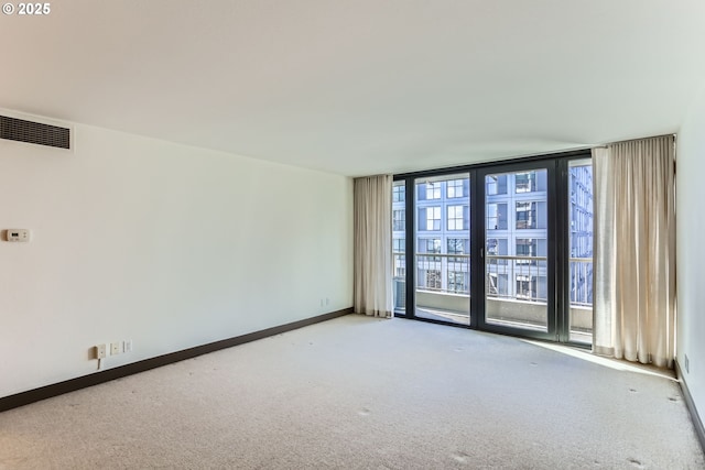 carpeted spare room featuring baseboards, floor to ceiling windows, and visible vents