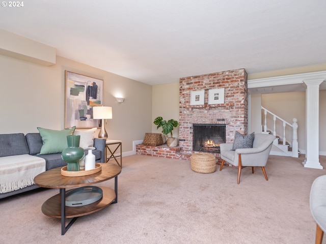 living room with a brick fireplace, carpet floors, and decorative columns