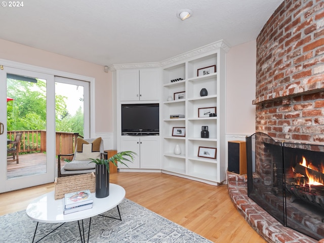 living room featuring a brick fireplace and light hardwood / wood-style flooring