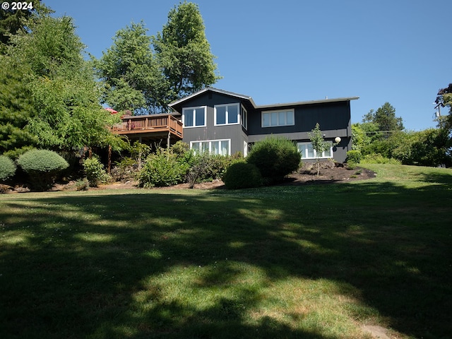 back of property featuring a wooden deck and a yard