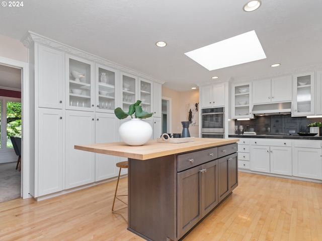 kitchen featuring white cabinetry, a skylight, wooden counters, and stainless steel double oven