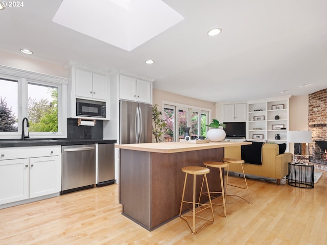 kitchen with sink, plenty of natural light, stainless steel appliances, a center island, and white cabinets