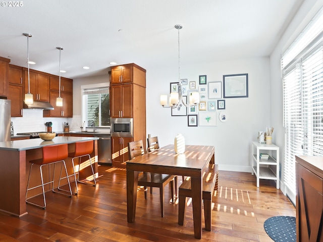 dining room with wood-type flooring, sink, and a notable chandelier