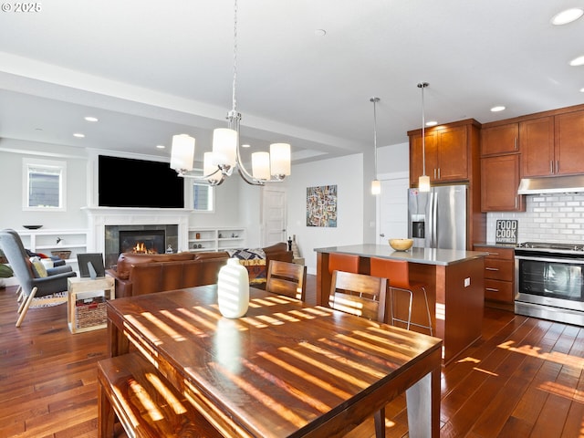 dining room featuring a notable chandelier, a tile fireplace, and dark hardwood / wood-style floors