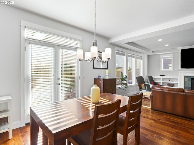 dining space featuring a fireplace, a tray ceiling, dark hardwood / wood-style flooring, and a chandelier