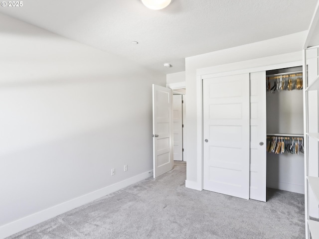 unfurnished bedroom featuring a closet, light carpet, and a textured ceiling