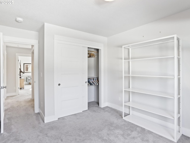 unfurnished bedroom with light colored carpet, a textured ceiling, and a closet