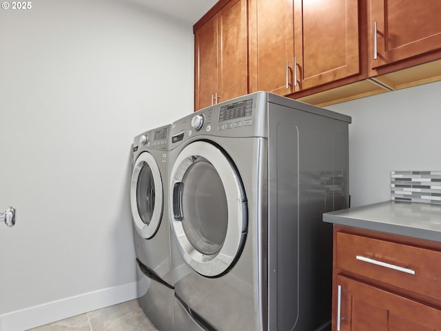 laundry room featuring cabinets, washing machine and clothes dryer, and light tile patterned flooring