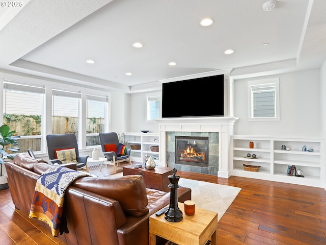 living room featuring a tile fireplace, dark hardwood / wood-style flooring, and a tray ceiling