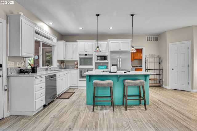 2672 SE Vista Way, Gresham, OR 97080 - kitchen featuring appliances with stainless steel finishes, light wood-style flooring, white cabinetry, a kitchen island, and recessed lighting