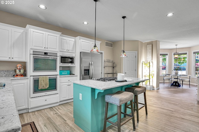 2672 SE Vista Way, Gresham, OR 97080 - kitchen with stainless steel appliances, white cabinetry, light wood finished floors, a kitchen island, and recessed lighting
