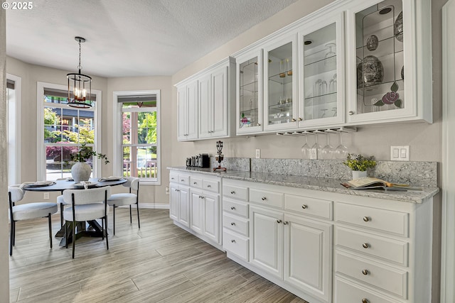 2672 SE Vista Way, Gresham, OR 97080 - kitchen featuring white cabinets, hanging light fixtures, glass insert cabinets, light stone countertops, and a chandelier