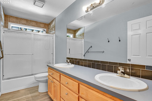 2672 SE Vista Way, Gresham, OR 97080 - full bathroom featuring toilet, double vanity, backsplash, bath / shower combo with glass door, and wood finished floors