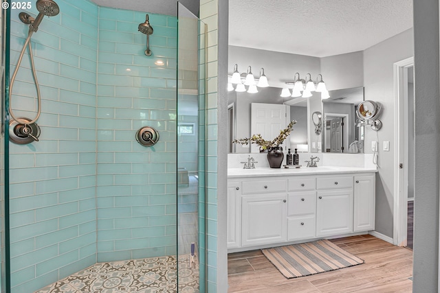 2672 SE Vista Way, Gresham, OR 97080 - bathroom featuring a tile shower, wood finished floors, double vanity, a textured ceiling, and baseboards