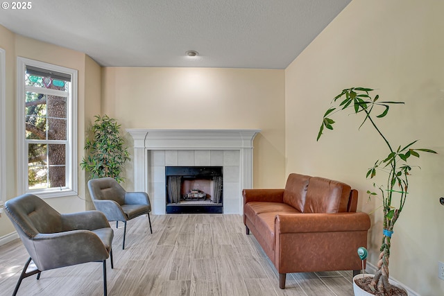 2672 SE Vista Way, Gresham, OR 97080 - sitting room featuring light wood finished floors, a tiled fireplace, baseboards, and a textured ceiling