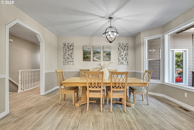 2672 SE Vista Way, Gresham, OR 97080 - dining room featuring light wood-type flooring, a chandelier, baseboards, arched walkways, and a textured ceiling