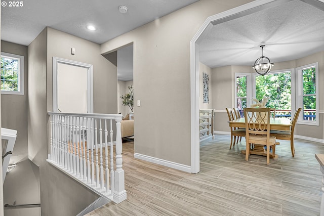 2672 SE Vista Way, Gresham, OR 97080 - hallway featuring baseboards, a textured ceiling, a chandelier, healthy amount of natural light, and light wood-type flooring
