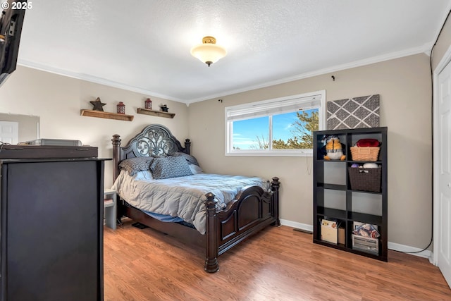 bedroom with ornamental molding, baseboards, a textured ceiling, and light wood finished floors