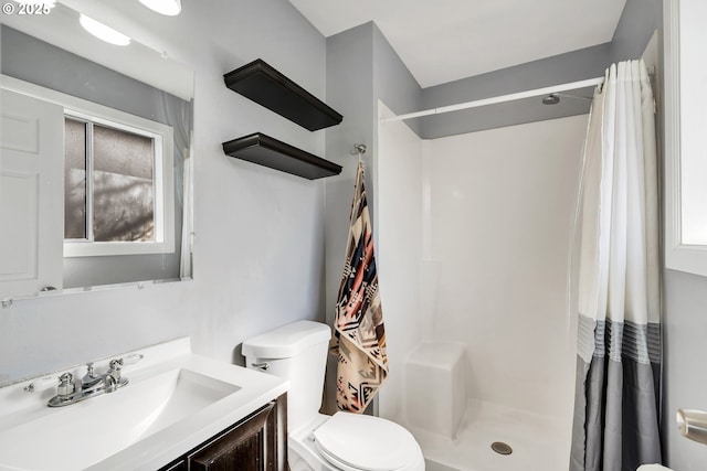 bathroom with a shower stall, toilet, and vanity