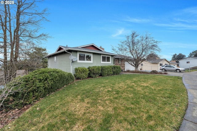 view of front of house with an attached garage, driveway, a chimney, and a front yard