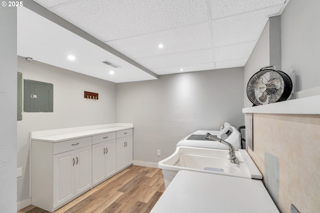 laundry area with light wood finished floors, electric panel, baseboards, visible vents, and recessed lighting