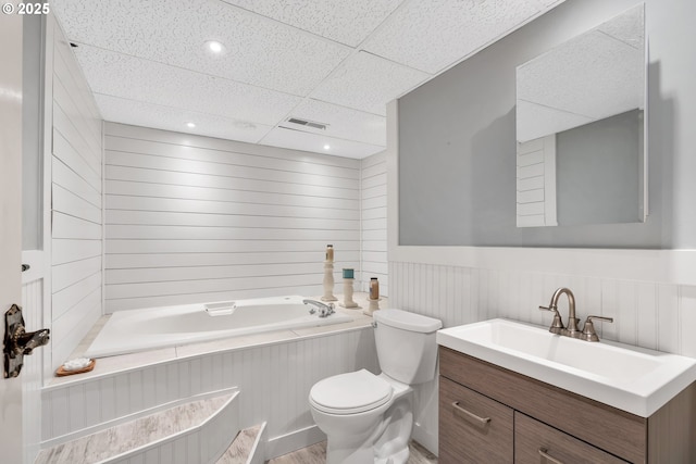 bathroom featuring visible vents, toilet, a wainscoted wall, a paneled ceiling, and a bath